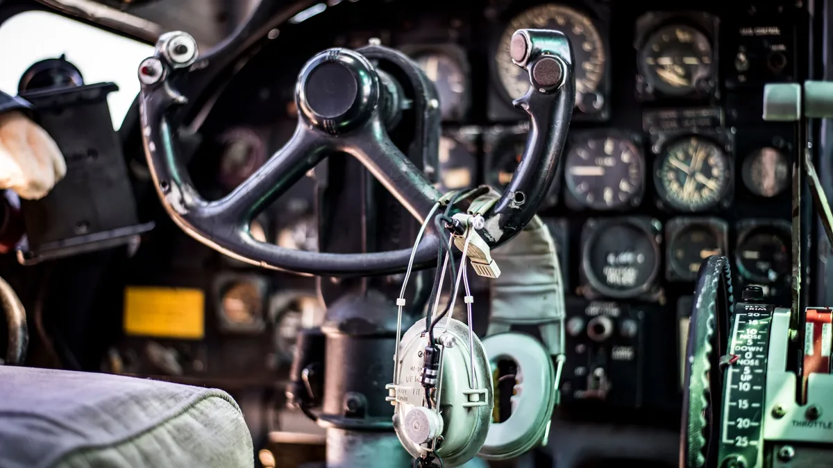 A cockpit with a control yoke, a headset, and a panel of gauges and dials.