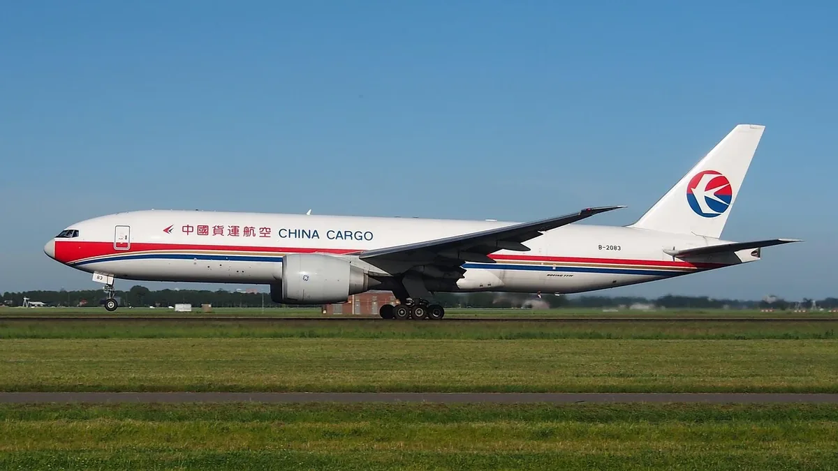 A white China Cargo plane on a runway, with a red stripe running along its side and a blue, red, and white logo on its tail.