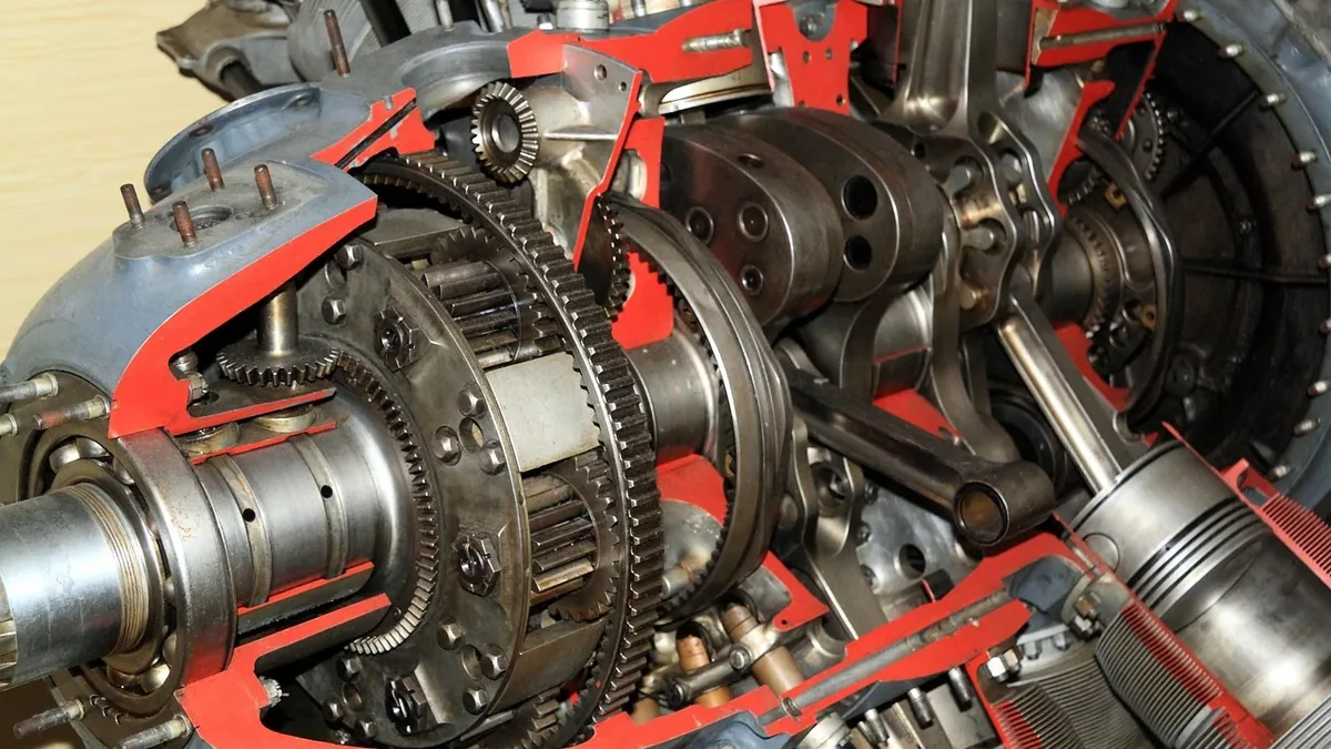 A close-up view of a complex mechanical device, likely an aircraft engine, with visible gears, shafts, and other metal components.