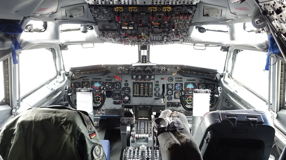 The cockpit of an airplane, with the pilot's hands on the controls and the instrument panel in front of them.